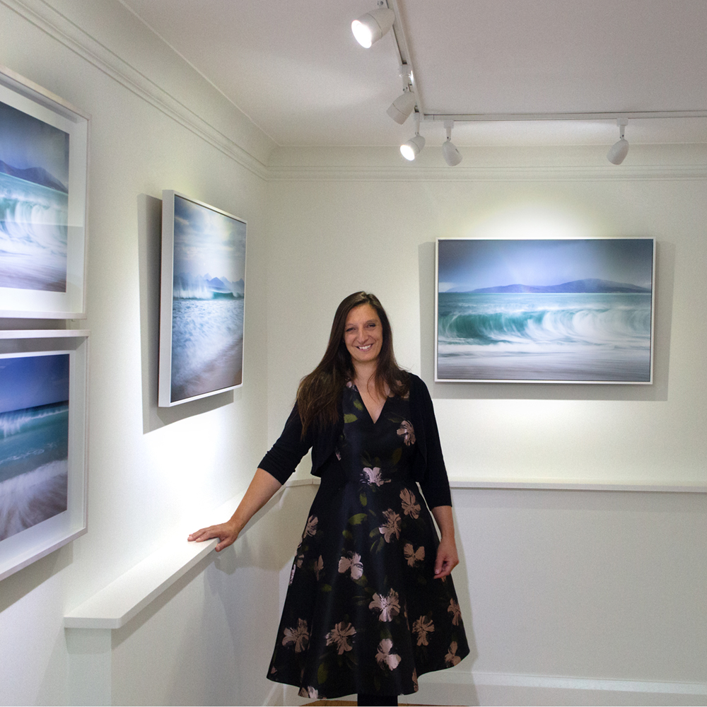 Margaret Soraya at the private view of her Bosham Gallery exhibition, surrounded by large-format framed Hebridean sea photographs<br />
