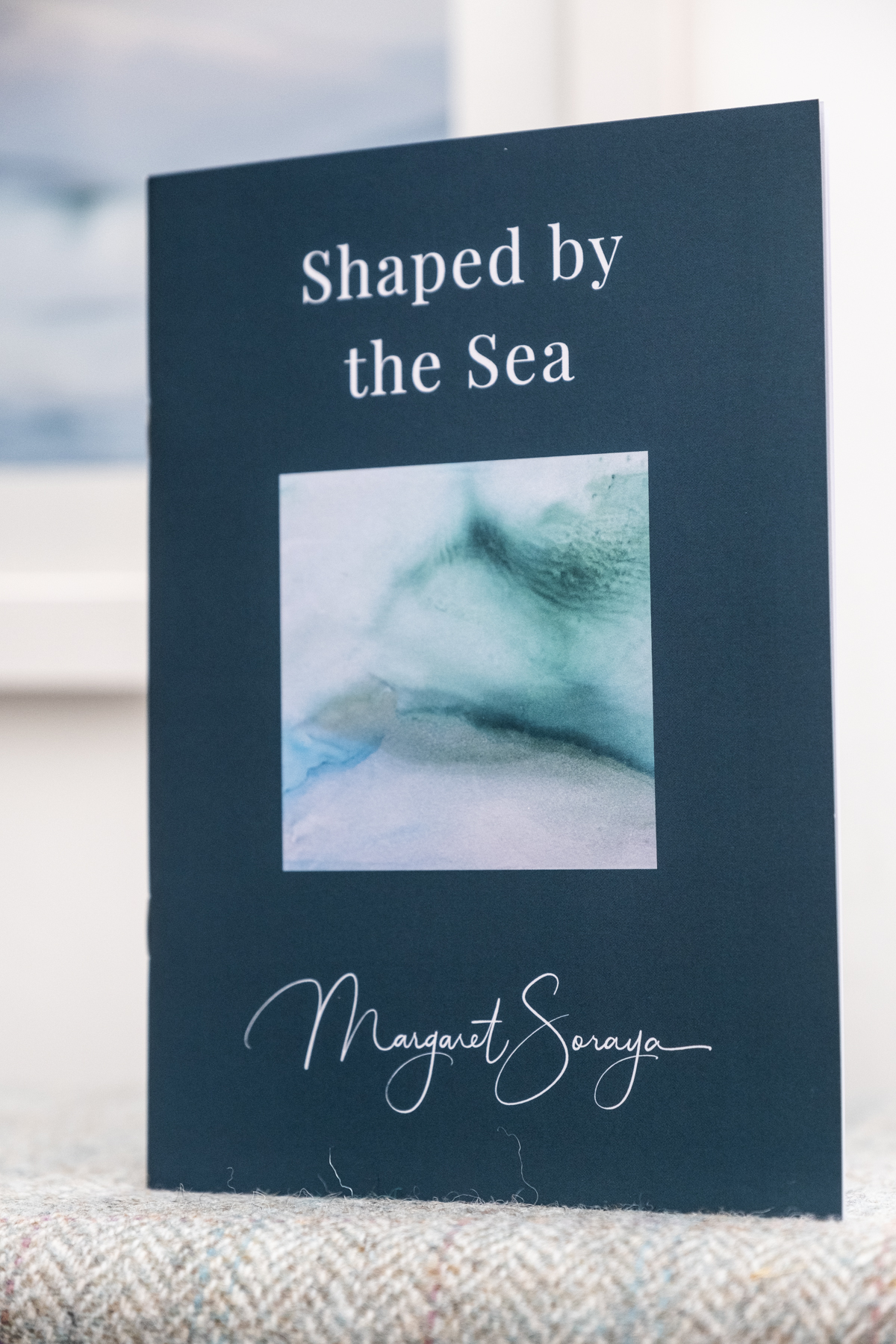 Shaped by the Sea poetry book by Margaret Soraya, dark teal cover with sea painting and signature, Isle of Harris