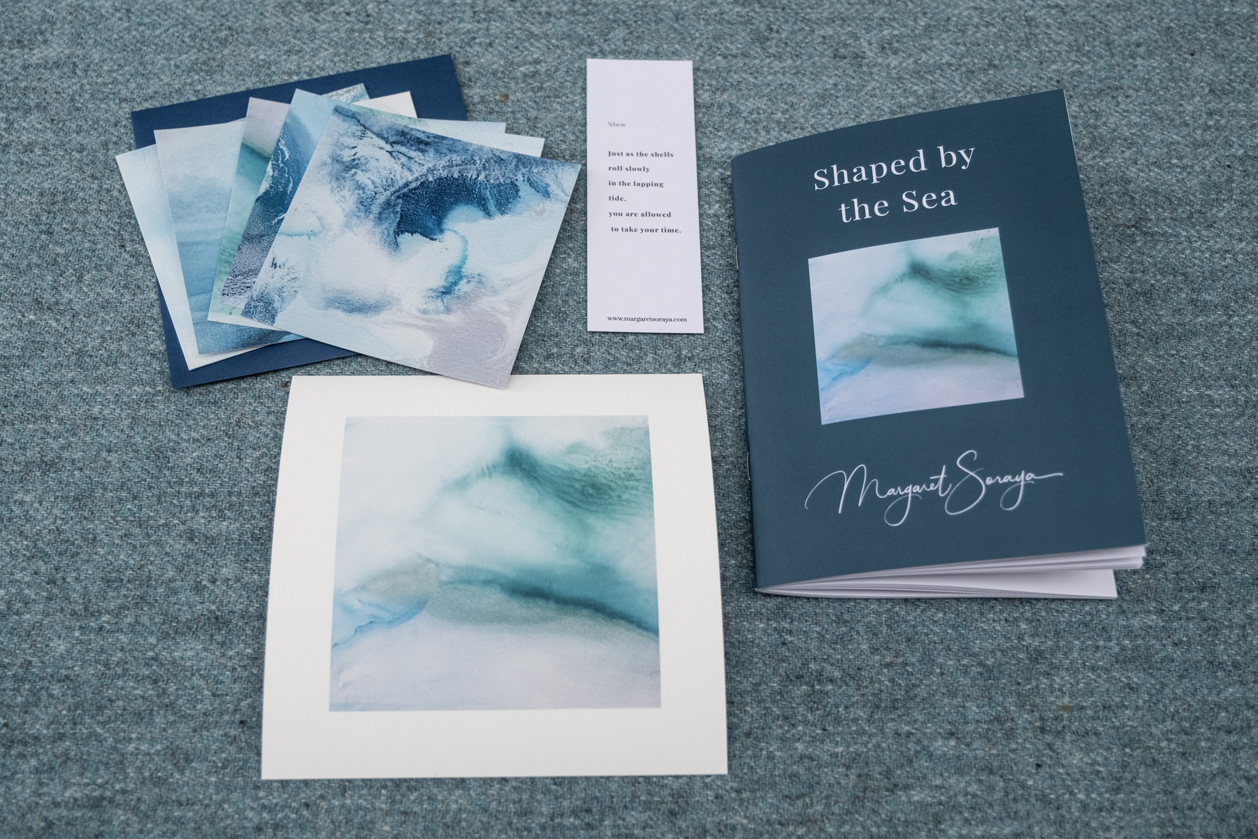 Open spread of Shaped by the Sea showing the poem The Beach Remains alongside a soft teal watercolour painting